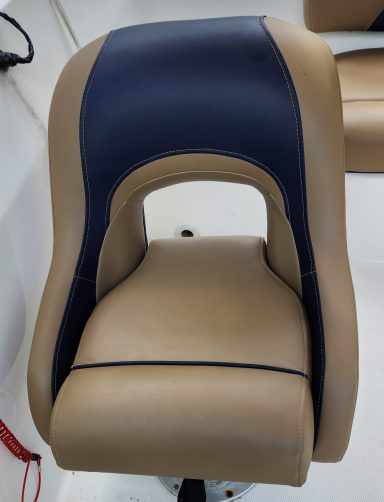 captains chair tan and blue Brown and navy blue padded boat seat with a cut-out design.